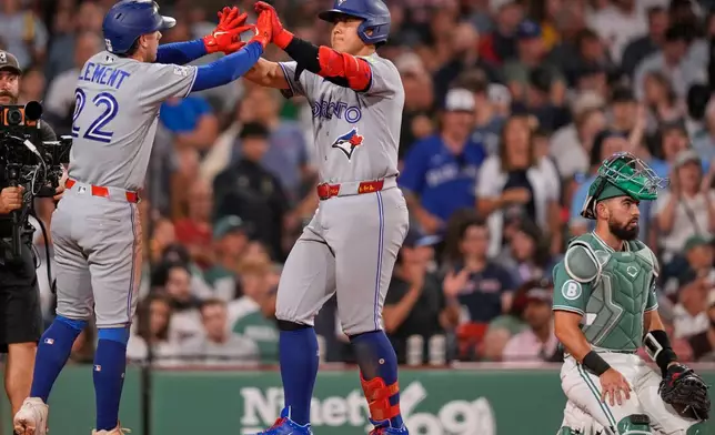 Toronto Blue Jays' Kazuma Okamoto, center, is congratuled by Ernie Clement (22) while passing Boston Red Sox's Connor Wong, right, on his three-run, home run during the seventh inning of a baseball game, Friday, July 24, 2026, in Boston. (AP Photo/Charles Krupa)