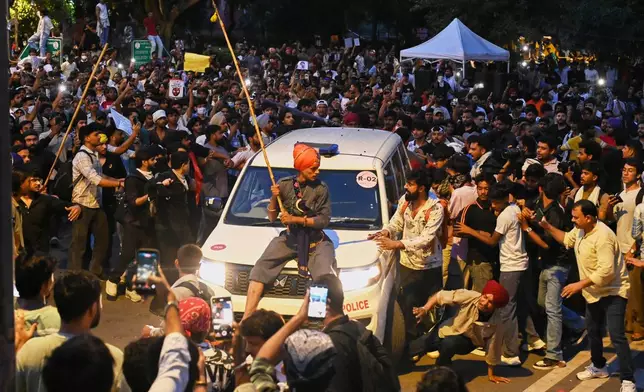A protestor sits on the hood of a police car during a demonstration demanding educational reforms as part of the Cockroach Janta Party's ongoing protest movement in New Delhi, India, Wednesday, July 22, 2026. (AP Photo/Vipin)