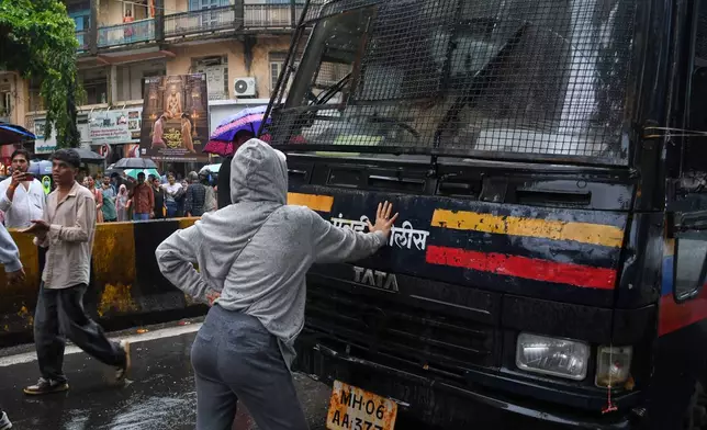 Rhiya Ahir, a model, blocks a police van carrying detained protesters during a demonstration demanding educational reforms as part of the Cockroach Janta Party's ongoing protest movement in Mumbai, India, Wednesday, July 22, 2026. (AP Photo/Ashish Vaishnav)