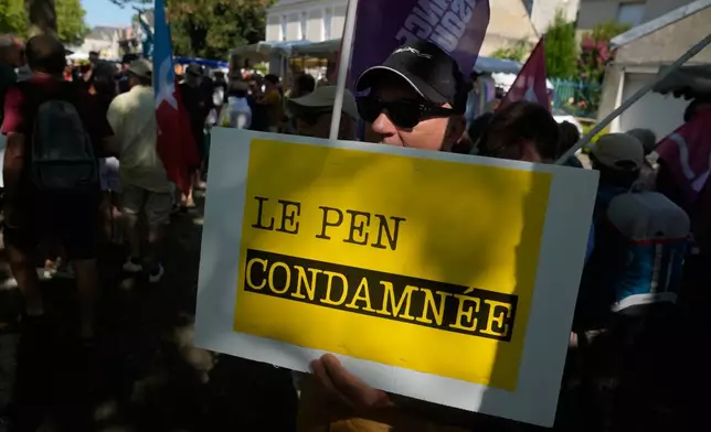 A protestor holds a placard reading: Le Pen convicted, during a protest against the visit of far-right leader Marine Le Pen in La Fleche, western France, Wednesday, July 8, 2026. (AP Photo/Michel Euler)