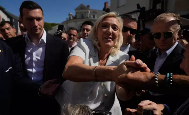 Far-right leader Marine Le Pen and Far-right party National Rally president Jordan Bardella arrive to visit a market in La Fleche, western France Wednesday, July. 8, 2026. (AP Photo/Michel Euler)