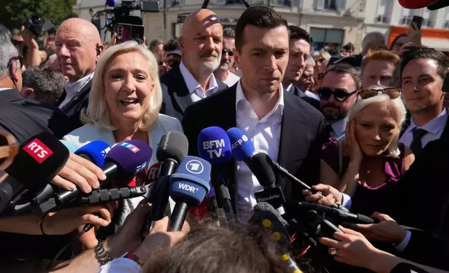 Far-right leader Marine Le Pen and Far-right party National Rally president Jordan Bardella answer journalists as they arrive to visit a market in La Fleche, western France Wednesday, July. 8, 2026. (AP Photo/Michel Euler)