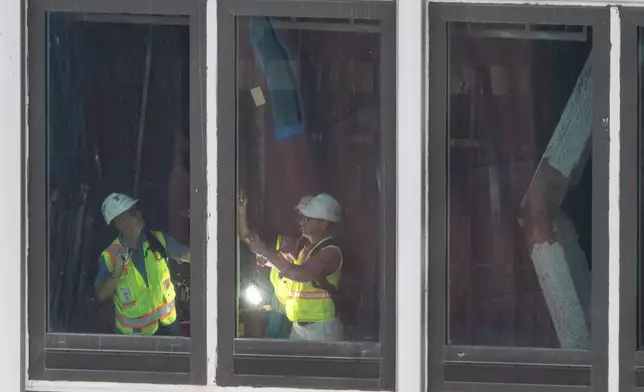 People inspect a buckled support beam inside 235 East 42nd Street, Wednesday, July 8, 2026, in New York. (AP Photo/Yuki Iwamura)