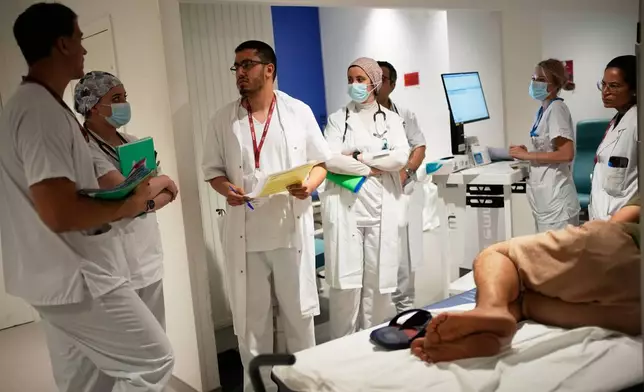 Doctors and nurses take care of a patient at the emergency department of the Paris-Saclay Hospital, outside Paris, Tuesday June 30, 2026. (AP Photo/Christophe Ena )