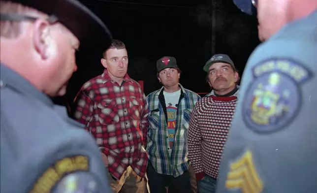 FILE - Maine loggers Stacey Kelly, second from left, Troy Jackson, and Hilton Hafford are threatened with arrest by Maine State Police if they continue to block access to Canadian woodsmen at the border at St. Pamphile, Quebec, Monday, Oct. 26, 1998. (AP Photo/Robert F. Bukaty,File)