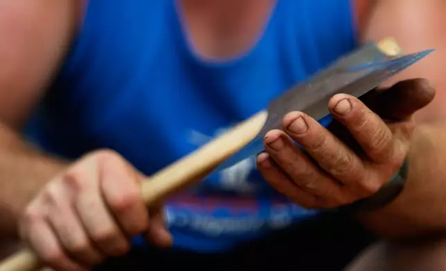 Nate Hodges, of California, tests the blade of his axe by grazing his skin before competing in the Lumberjack World Championships Friday, July 17, 2026, in Hayward, Wis. (AP Photo/Ellen Schmidt)