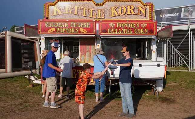 Children play with blow-up axes while waiting in line for concessions during the Lumberjack World Championships, Friday, July 17, 2026, in Hayward, Wis. (AP Photo/Ellen Schmidt)