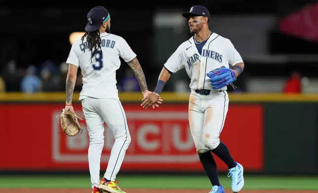 Seattle Mariners' Julio Rodríguez high fives J.P. Crawford after defeating the Los Angeles Angels in a baseball game Tuesday, June 30, 2026, in Seattle. (AP Photo/Kevin Ng)