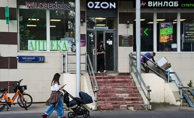 A woman pushes a baby stroller past a shopping area featuring an outlet of Russia's major online retailer Wildberries in Moscow on Wednesday, July 22, 2026. (AP Photo/Alexander Zemlianichenko)