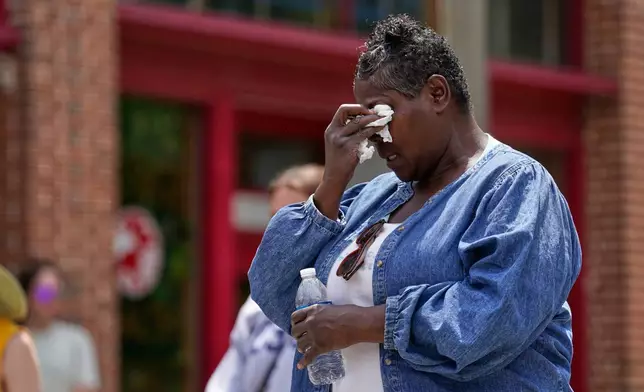 Mourners gather around a memorial at the site where a man was shot and killed on Wednesday by Madison police, Thursday, July 23, 2026, in Madison, Wis. (AP Photo/Kayla Wolf)