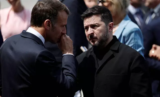 French President Emmanuel Macron speaks with Ukraine's President Volodymyr Zelenskiy as they leave after the annual Bastille Day military parade on the Place de la Concorde in Paris, France, Tuesday, July 14, 2026. (Benoit Tessier/Pool photo via AP)