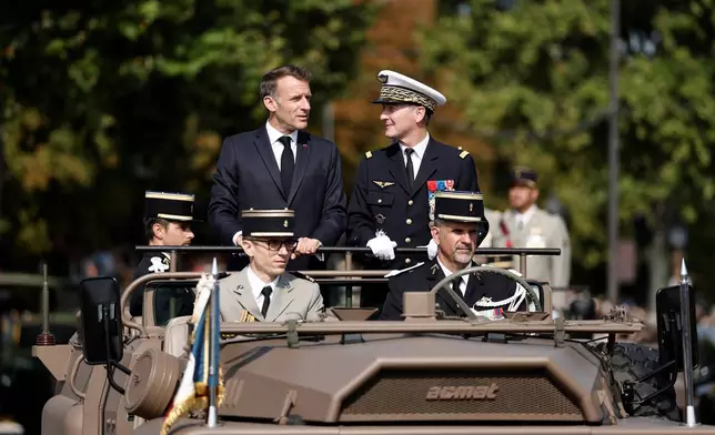 French President Emmanuel Macron, left, stands in the command car with General Chief of Staff of the French Armed Forces Fabien Mandon during the annual Bastille Day military parade on the Champs-Elysees avenue in Paris, France, Tuesday, July 14, 2026. (Benoit Tessier/Pool Photo via AP)