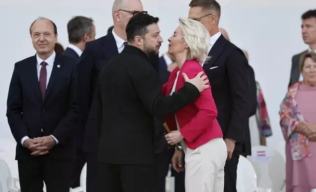European Commission President Ursula von der Leyen, centre right, greets Ukraine's President Volodymyr Zelenskiyy before the start of the annual Bastille Day military parade in Paris, France, Tuesday, July 14, 2026. (Benoit Tessier/Pool Photo via AP)
