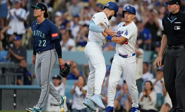 Los Angeles Dodgers' Andy Pages, second from left, collides with Tommy Edman, second from right, as he scores on a double by Mookie Betts as Seattle Mariners starting pitcher Bryan Woo walks away during the first inning of a baseball game Thursday, July 30, 2026, in Los Angeles. (AP Photo/Mark J. Terrill)
