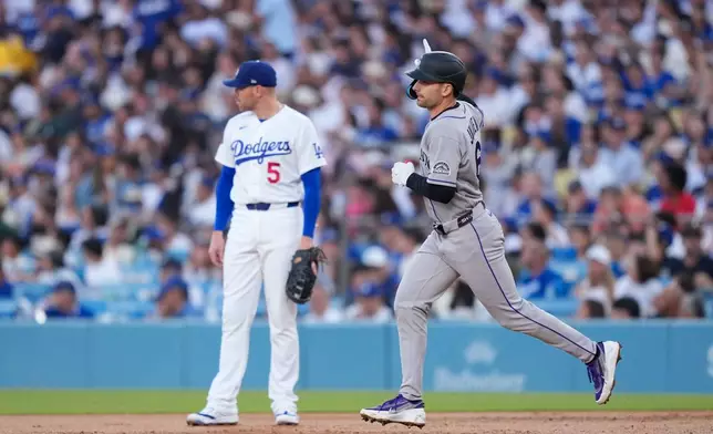 Colorado Rockies' Edouard Julien, right, heads to second for a solo home run as Los Angeles Dodgers first baseman Freddie Freeman stands by during the second inning of a baseball game Wednesday, July 8, 2026, in Los Angeles. (AP Photo/Mark J. Terrill)