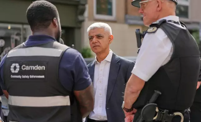 London Mayor Sadiq Khan, centre, and Mark Rowley, Commissioner of Police of the Metropolis, right, speak to staff, during a walkabout through the borough of Camden in London, Thursday, July 23, 2026. (AP Photo/Kirsty Wigglesworth)