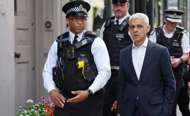 London Mayor Sadiq Khan, right, with Police Constable Opara speak, during a walkabout through the borough of Camden in London, Thursday, July 23, 2026. (AP Photo/Kirsty Wigglesworth)