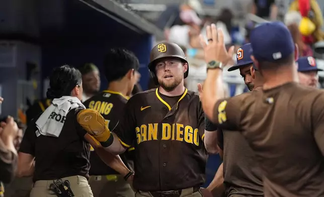San Diego Padres' Jake Cronenworth celebrates with teammates after scoring on a double by designated hitter Manny Machado during the fifth inning of a baseball game against the Miami Marlins, Sunday, July 26, 2026, in Miami. (AP Photo/Rebecca Blackwell)