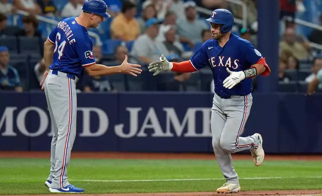 Texas Rangers' Austin Wynns celebrates his solo home run off Tampa Bay Rays pitcher Steven Matz with third base coach Corey Ragsdale (64) during the seventh inning of a baseball game Tuesday, July 28, 2026, in St. Petersburg, Fla. (AP Photo/Chris O'Meara)