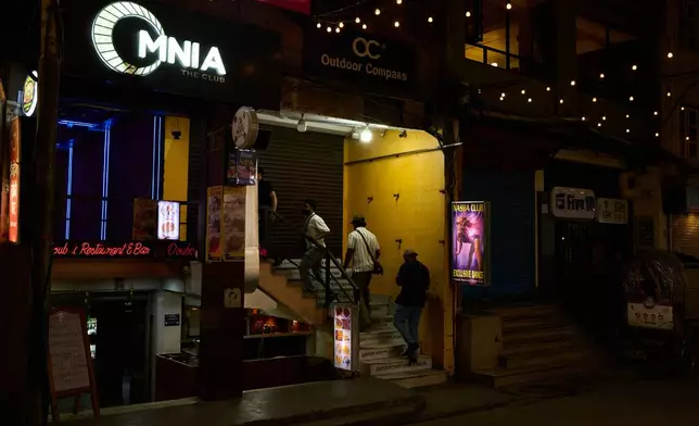 Men enter a club in Kathmandu, Nepal, Thursday, May 21, 2026. (AP Photo/Bram Janssen)