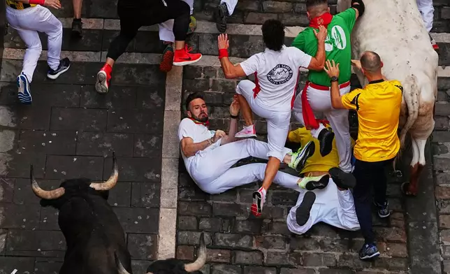 Revelers run alongside Victoriano del Río's fighting bulls during the third running of the bulls at the San Fermín festival in Pamplona, Spain, Thursday, July 9, 2026. (AP Photo/Miguel Oses)