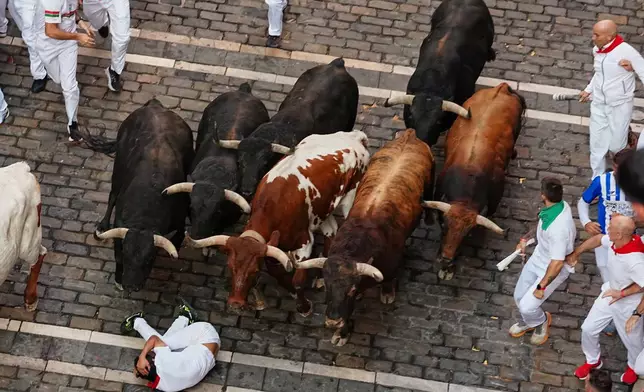 A reveler falls in front of Victoriano del Río's fighting bulls during the third running of the bulls at the San Fermín festival in Pamplona, Spain, Thursday, July 9, 2026. (AP Photo/Miguel Oses)