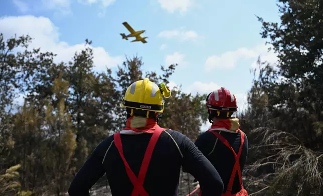 Firefighters look at an amphibious firefighting aircraft as they battle fires near Lege-Cap-Ferret, southwestern France, Friday, July 31, 2026. (AP Photo/Emma Da Silva)