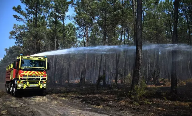 A firefighting crew hose down a smoldering forest near Lauros, during wildfires in southwestern France, Thursday, July 30, 2026. (AP Photo/Emma Da Silva)
