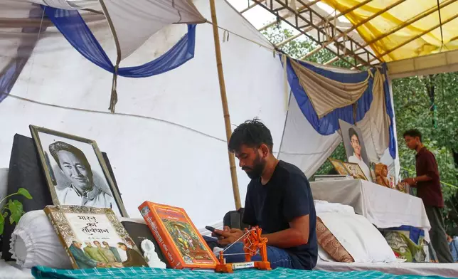 Abhijeet Dipke, founder of the Cockroach Janta Party, sits by a portrait of hunger-striking activist Sonam Wangchuk during a protest in New Delhi, Tuesday, July 21, 2026. (AP Photo/Shekhar Yadav)
