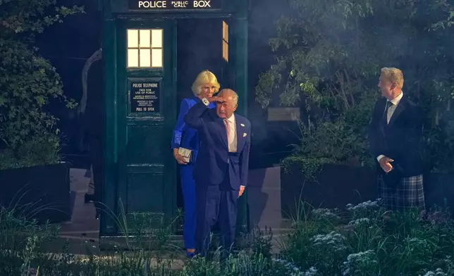 Britain's King Charles III, center, and Queen Camilla look as they step out of the Doctor Who TARDIS police box as Sir Chris Hoy, right, looks on at the start of the Commonwealth Games opening ceremony in Glasgow, Scotland, Thursday, July 23, 2026. (AP Photo/Manish Swarup)
