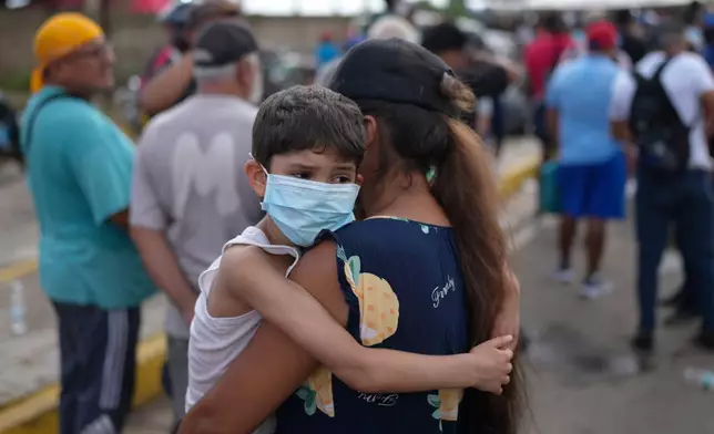Ogleisys Cisneros holds her son, Santiago Medina, while waiting in line for government humanitarian aid, days after an earthquake struck in La Guaira, Venezuela, Tuesday, June 30, 2026. (AP Photo/Matias Delacroix)