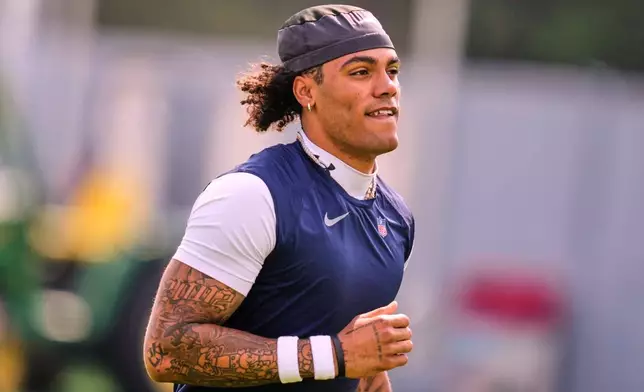 New England Patriots cornerback Christian Gonzalez (0) runs across a practice field during the team's NFL football training camp, Tuesday, July 28, 2026, in Foxborough, Mass. (AP Photo/Charles Krupa)