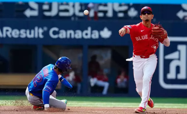 Blue Jays' Andres Gimenez tries to turn the double play but New York Mets' A.J Ewing is safe at first base during fourth inning MLB baseball action in Toronto on Wednesday, July 1, 2026. (Frank Gunn/The Canadian Press via AP)