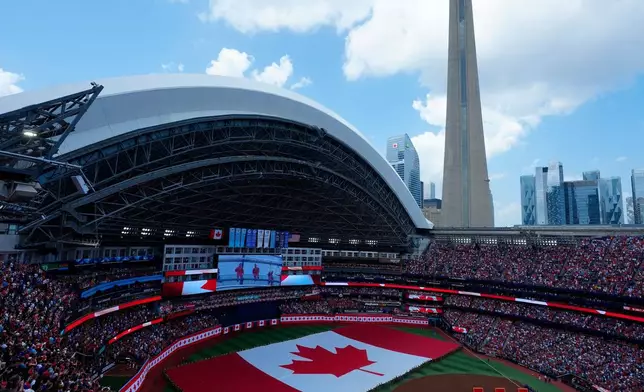 Fans watch as the Canadian flag is taken onto the field of play for Canada Day before the start of MLB baseball action between the Toronto Blue Jays and the New York Mets in Toronto on Wednesday, July 1, 2026. (Frank Gunn/The Canadian Press via AP)