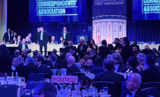 FILE - U.S. Secret Service agents respond near President Donald Trump and first lady Melania Trump during the White House Correspondents Dinner, Saturday, April 25, 2026, in Washington. (AP Photo/Alex Brandon, File)