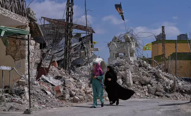 Lebanese women pass by houses that were destroyed in Israeli strikes during the war with Hezbollah in Froun village, southern Lebanon, Thursday, July 16, 2026. (AP Photo/Mohammed Zaatari)