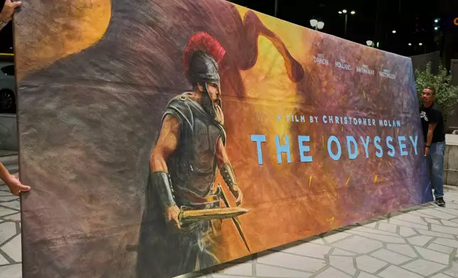 Workers install a hand-painted billboard, painted by artist Virginia Axioti, for Christopher Nolan's upcoming film "The Odyssey," starring Matt Damon as Odysseus, outside Athens' Athinaion cinema, Saturday, July 11, 2026. (AP Photo/Petros Giannakouris)