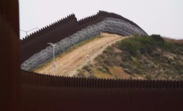FILE - Concertina wire lines the interior of a border wall separating Tijuana, Mexico, from the United States, June 4, 2025, in San Diego. (AP Photo/Gregory Bull, File)