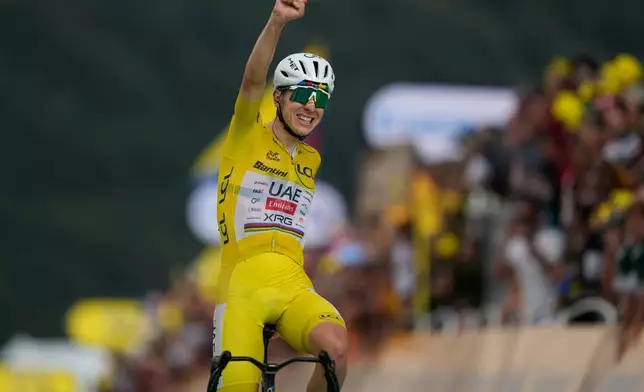 Slovenia's Tadej Pogacar, wearing the overall leader's yellow jersey, celebrates as he crosses the finish line to win the fourteenth stage of the Tour de France cycling race with start in Mulhouse and finish in Le Markstein Fellering, France, Saturday, July 18, 2026. (AP Photo/Mosa'ab Elshamy)