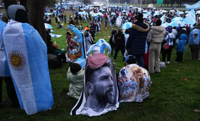 An Argentina fan wrapped in a flag bearing an image of Lionel Messi gathers outside the Argentine Football Association headquarters while waiting for the national team to arrive in Ezeiza, on the outskirts of Buenos Aires, Monday, July 20, 2026, following its World Cup final loss to Spain. (AP Photo/Rodrigo Abd)