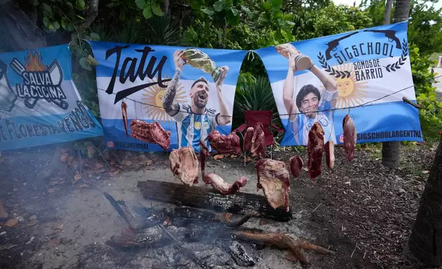 Argentine Angus beef hangs suspended over an outdoor fire as Argentina fans gather to celebrate and cheer on their team at a beachfront park in Miami Beach, Fla., Thursday, July 2, 2026, one day ahead of their World Cup round of 32 soccer match against Cape Verde. (AP Photo/Rebecca Blackwell)