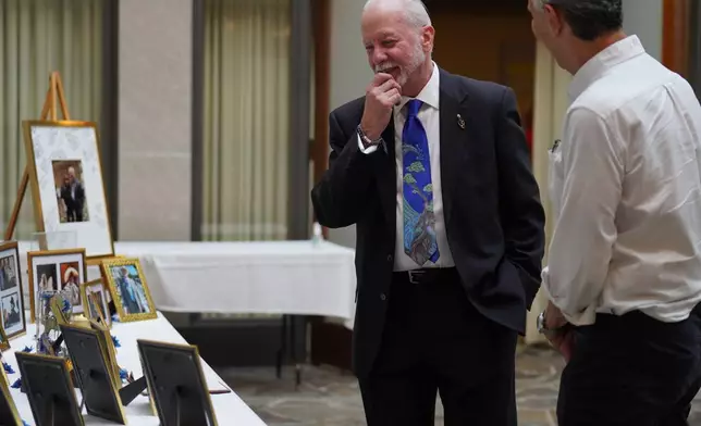 Rabbi Jeffrey Myers of the Tree of Life Congregation, left, reminisces over images presented at his retirement dinner celebration at Rodef Shalom Congregation in Pittsburgh on Friday, July 17, 2026. (AP Photo/Jessie Wardarski)