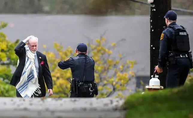 FILE - Rabbi Jeffrey Myers holds his head as he is escorted by police out of the Tree of Life Synagogue in the Squirrel Hill section of Pittsburgh, on Oct. 27, 2018, after a gunman fatally shot people while they worshipped. (Alexandra Wimley/Pittsburgh Post-Gazette via AP, File)