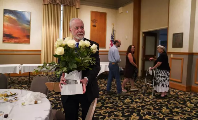 Rabbi Jeffrey Myers of the Tree of Life Congregation holds a bouquet of flowers while at his retirement dinner celebration on Friday, July 17, 2026, at Rodef Shalom Congregation in Pittsburgh. (AP Photo/Jessie Wardarski)