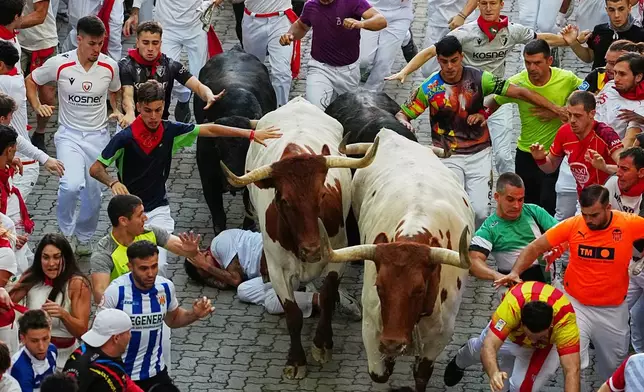 Revelers run alongside Jandilla's fighting bull during the eigth running of the bulls at the San Fermín festival in Pamplona, Spain, Tuesday, July 14, 2026. (AP Photo/Miguel Oses)