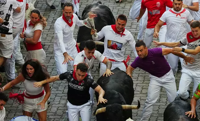 Revelers run alongside Jandilla's fighting bull during the eigth running of the bulls at the San Fermín festival in Pamplona, Spain, Tuesday, July 14, 2026. (AP Photo/Miguel Oses)