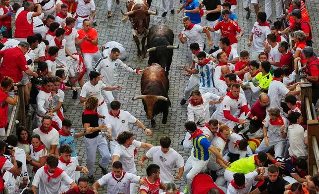 Revelers run alongside Jandilla's fighting bull during the eigth running of the bulls at the San Fermín festival in Pamplona, Spain, Tuesday, July 14, 2026. (AP Photo/Miguel Oses)
