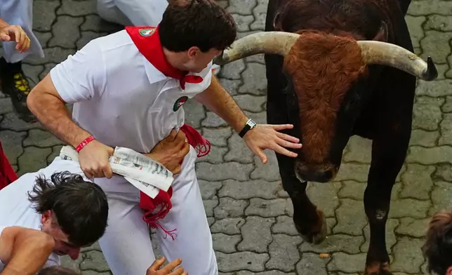 Revelers run alongside Jandilla's fighting bull during the eigth running of the bulls at the San Fermín festival in Pamplona, Spain, Tuesday, July 14, 2026. (AP Photo/Miguel Oses)