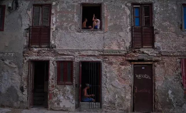 People catch the cool air from the street at their home's window during a blackout in Havana, Cuba, Friday, July 10, 2026. (AP Photo/Ramon Espinosa)