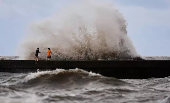 Children play near breaking waves on West End Pier on Lake Pontchartrain as Tropical Storm Bertha approaches the Louisiana Coast Wednesday, July 22, 2026, in New Orleans. (AP Photo/Gerald Herbert)